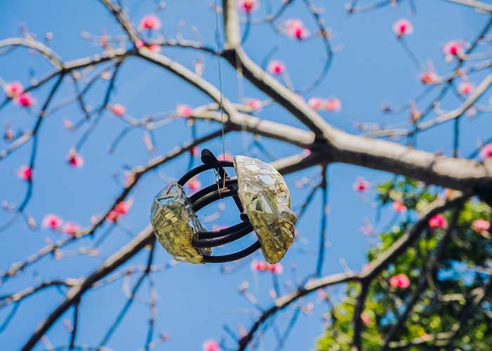 artwork sculpture haning from tree with pink flowers