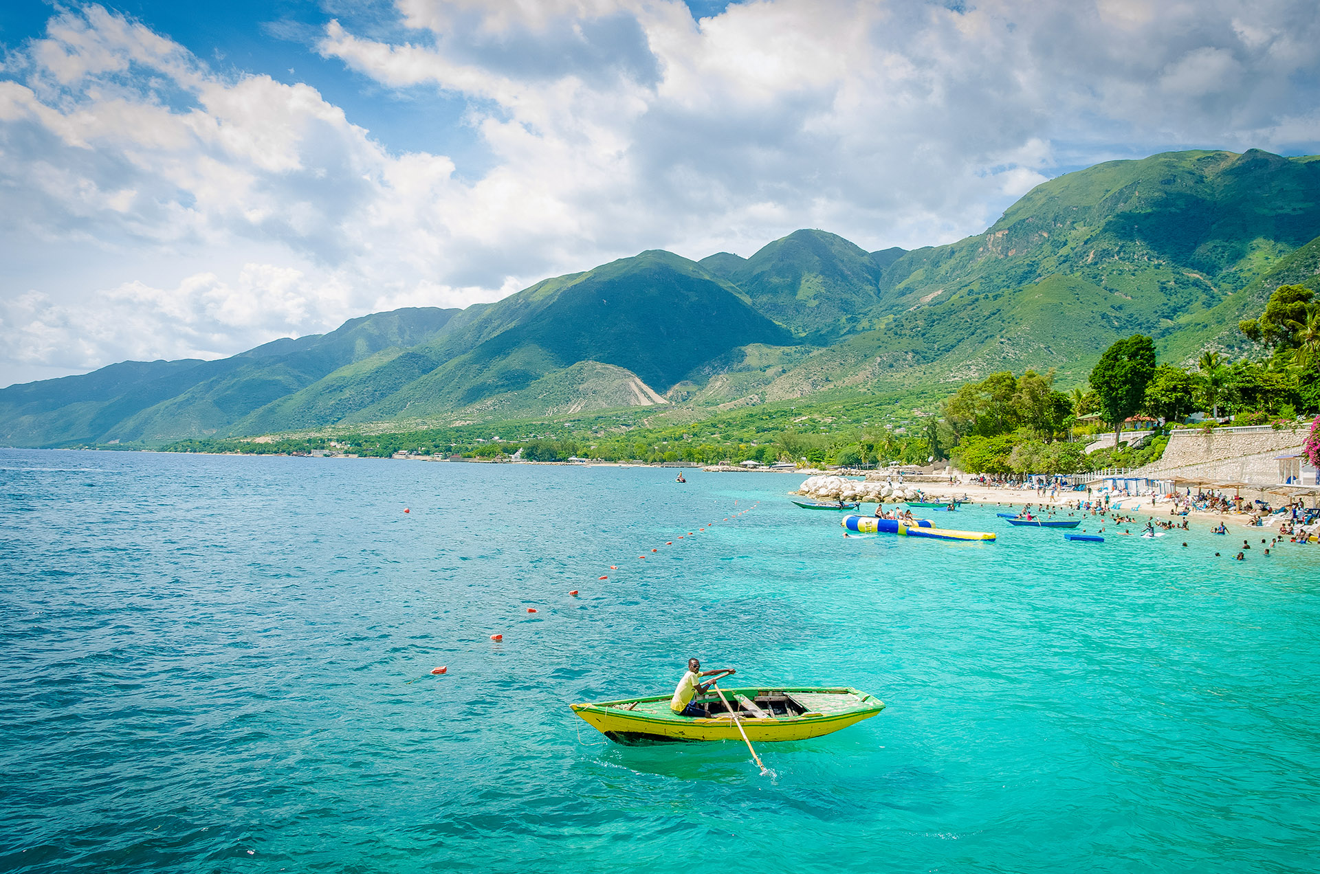 Boats and people swimming on the beach at Wahoo Bay,