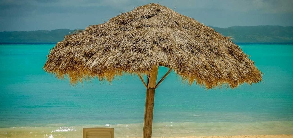 Deck chair under a thatch umbrella at Abaka Bay, Ile-a-vache, Haiti