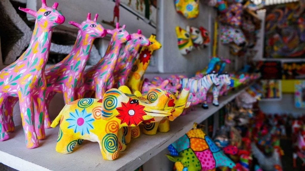 Colorfully-painted paper mache animals lined up on a shelf