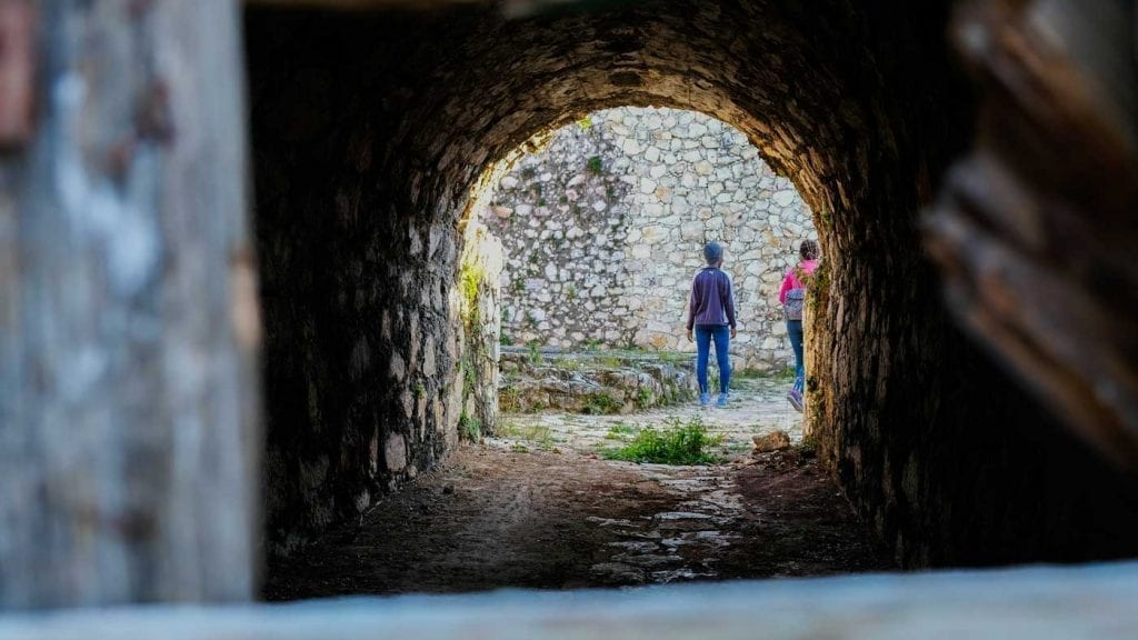 Two people seen through a dark tunnel at Fort Jacques, Haiti