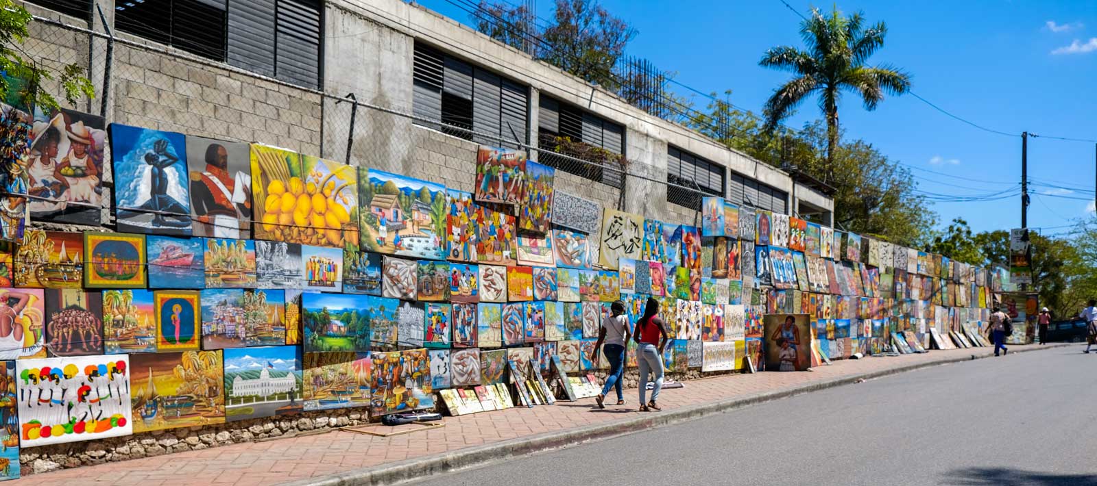 Colorful canvases on display on a fence along Rue Pinchinat