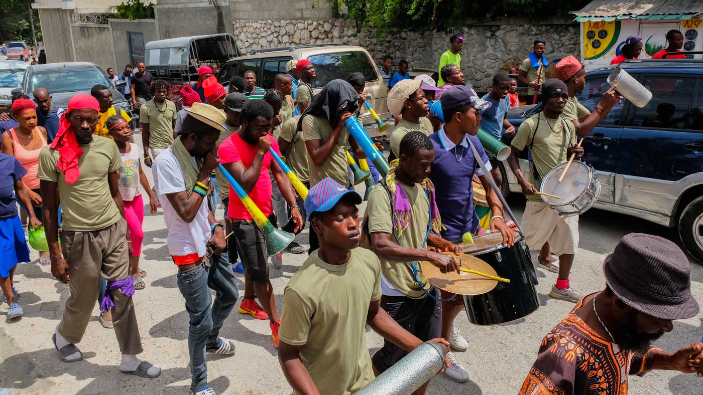group of haitian walking while playing on trumpets during rara festivities