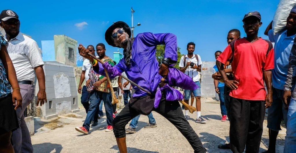 haitian man dressed in purple shirt with human bones celebrating fet gede