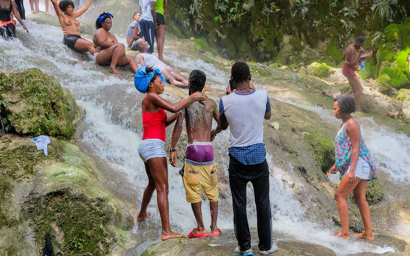 haitian pilgrims during a spiritual ritual by waterfall