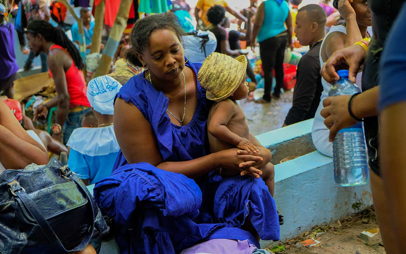 haitian woman in blue dress with small child in straw hat