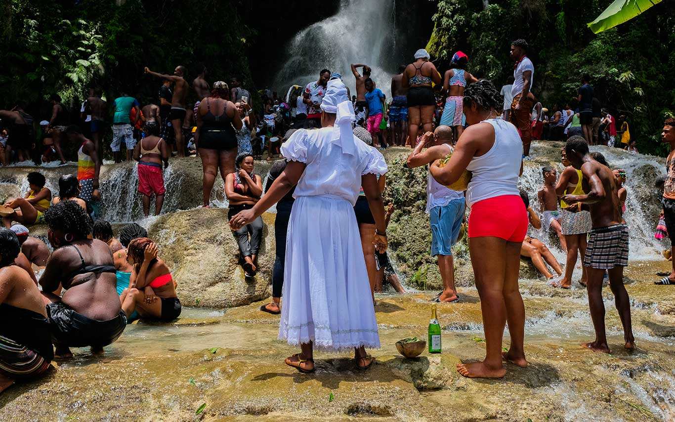 crowd of haitians preparing for a spiritual bath by waterfall