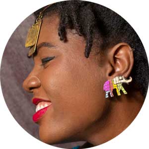 Portrait d'une femme haïtienne de profil portant des bijoux en or et une boucle d'oreille colorée en forme d'éléphant