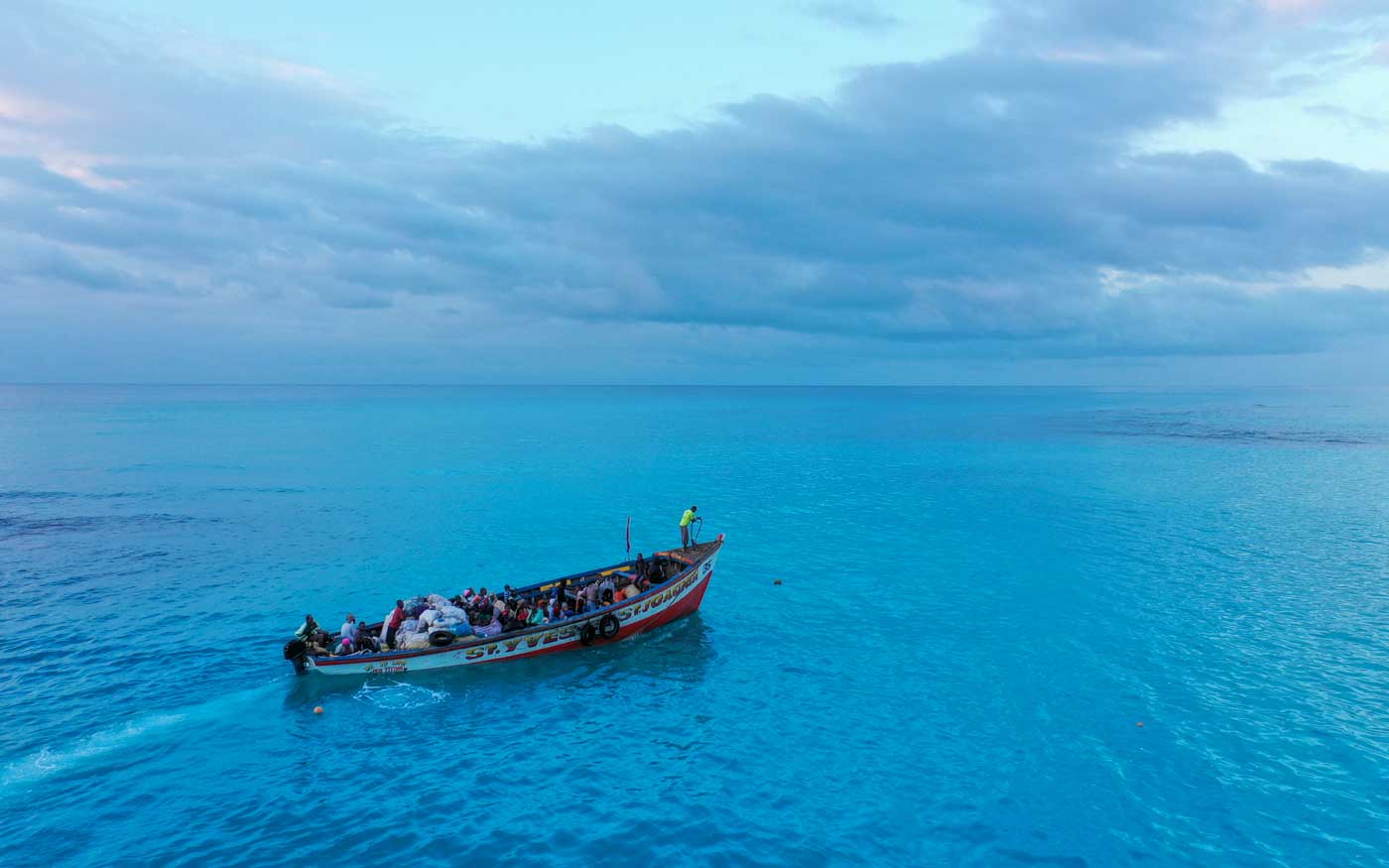 large wooden boat with haitians on the open ocean