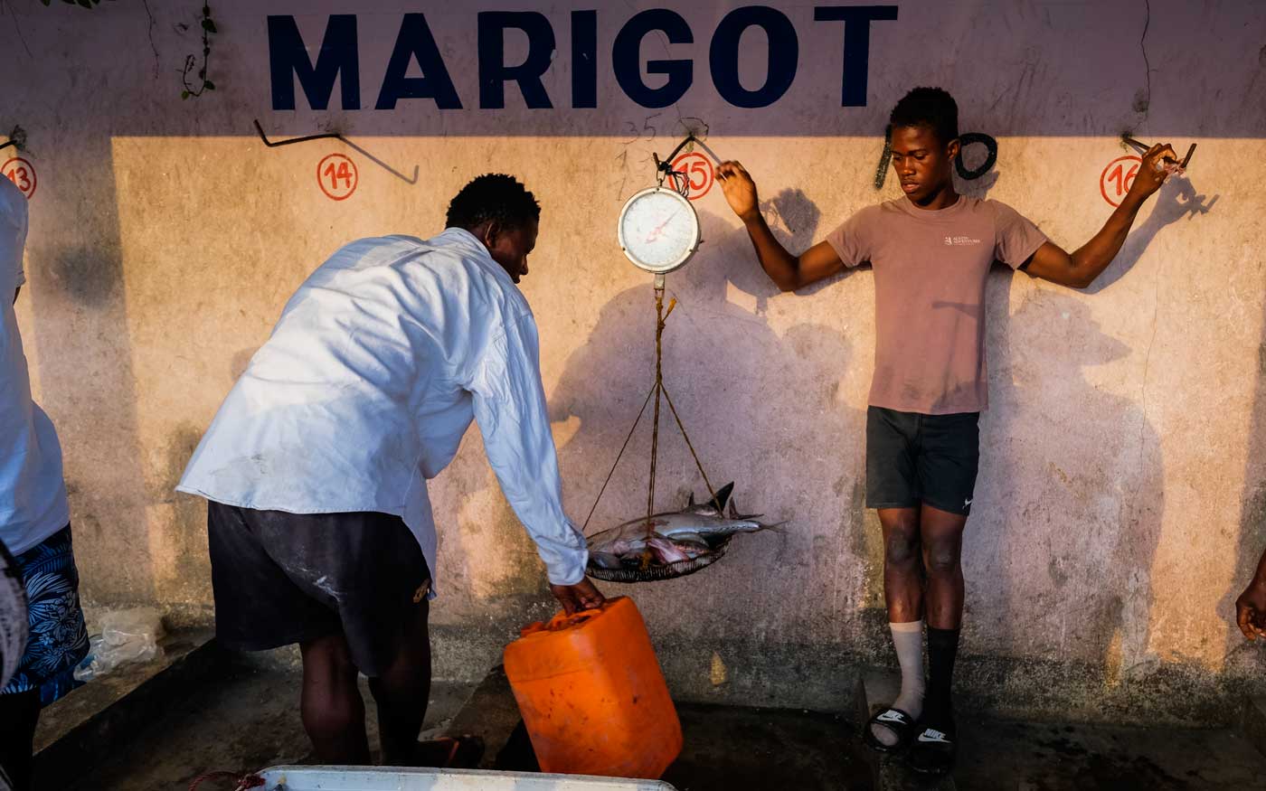 two haitians weighing fish at market