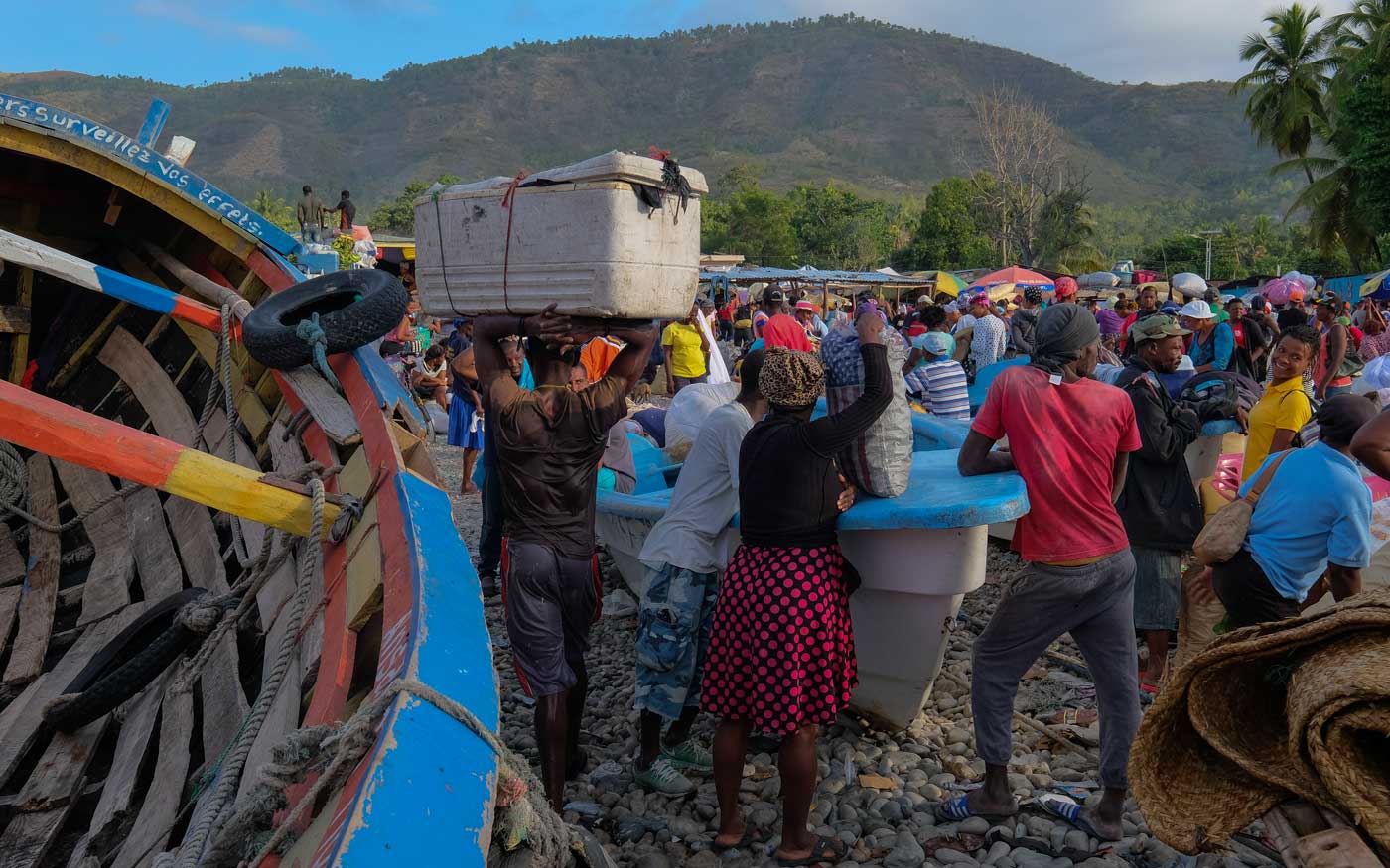 people at a haitian market place with boats