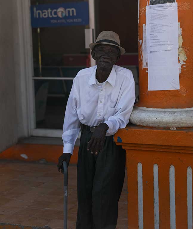 older haitian man in white shirt and black pants