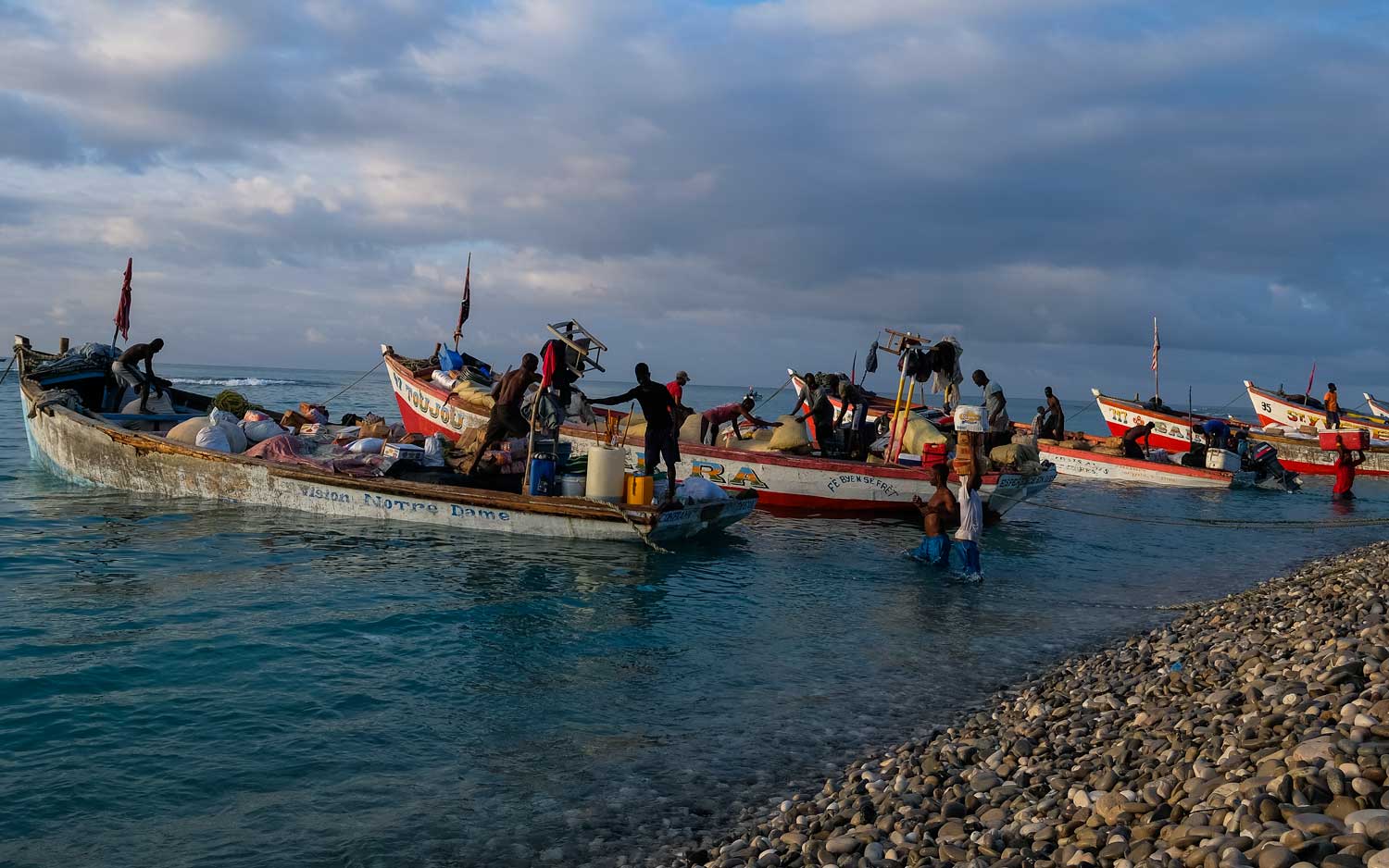 haitian men unloading large wooden boats