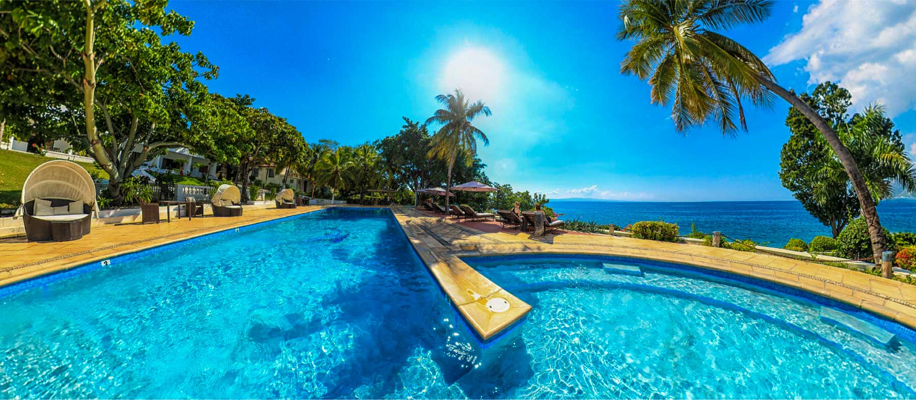 hotel pool by the ocean lined with palm trees