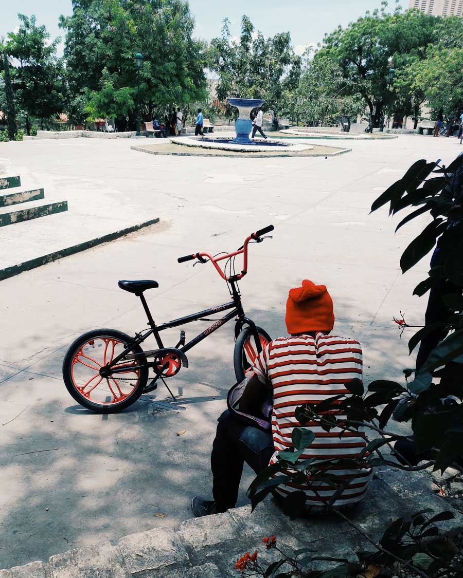 man sitting next to a parked bmx bike in public square