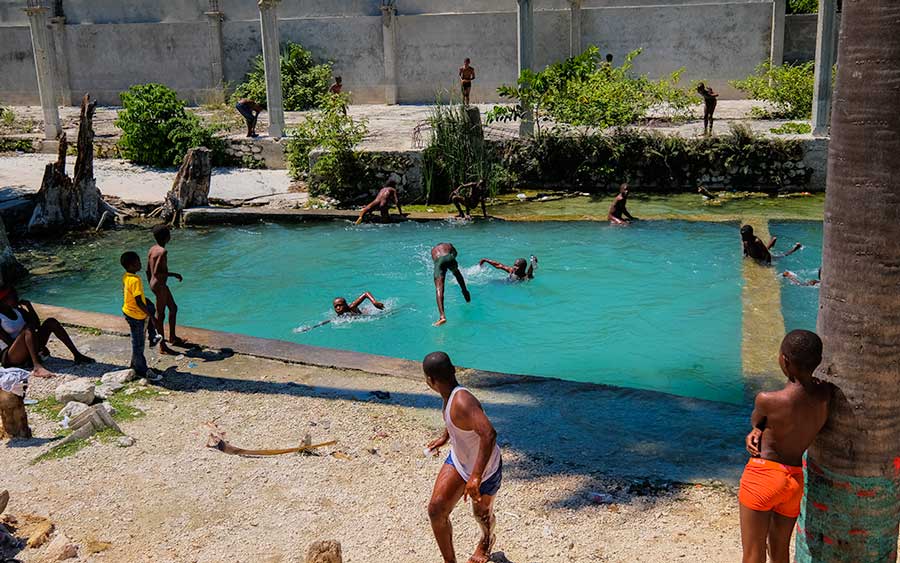 group of haitian kids swimming swimming in natural pool