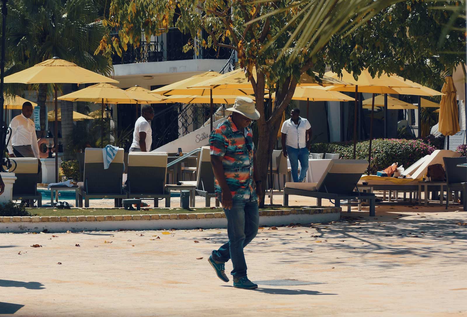 man walking in hotel area with parasols and lounge chairs