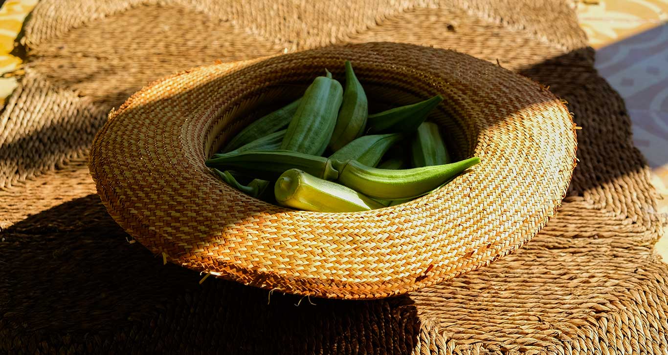 a straw hat filled with green okra