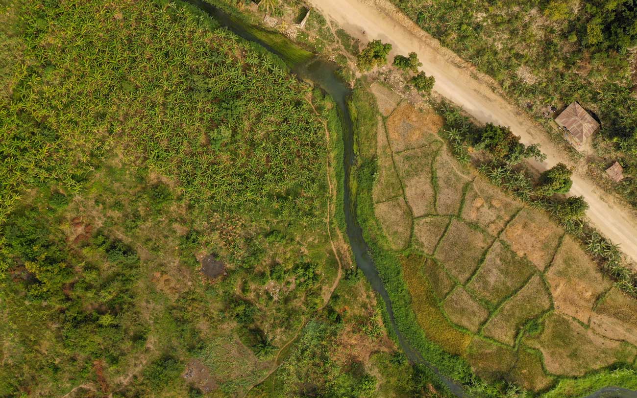 aerial view of farmers fields, river, road and plantation