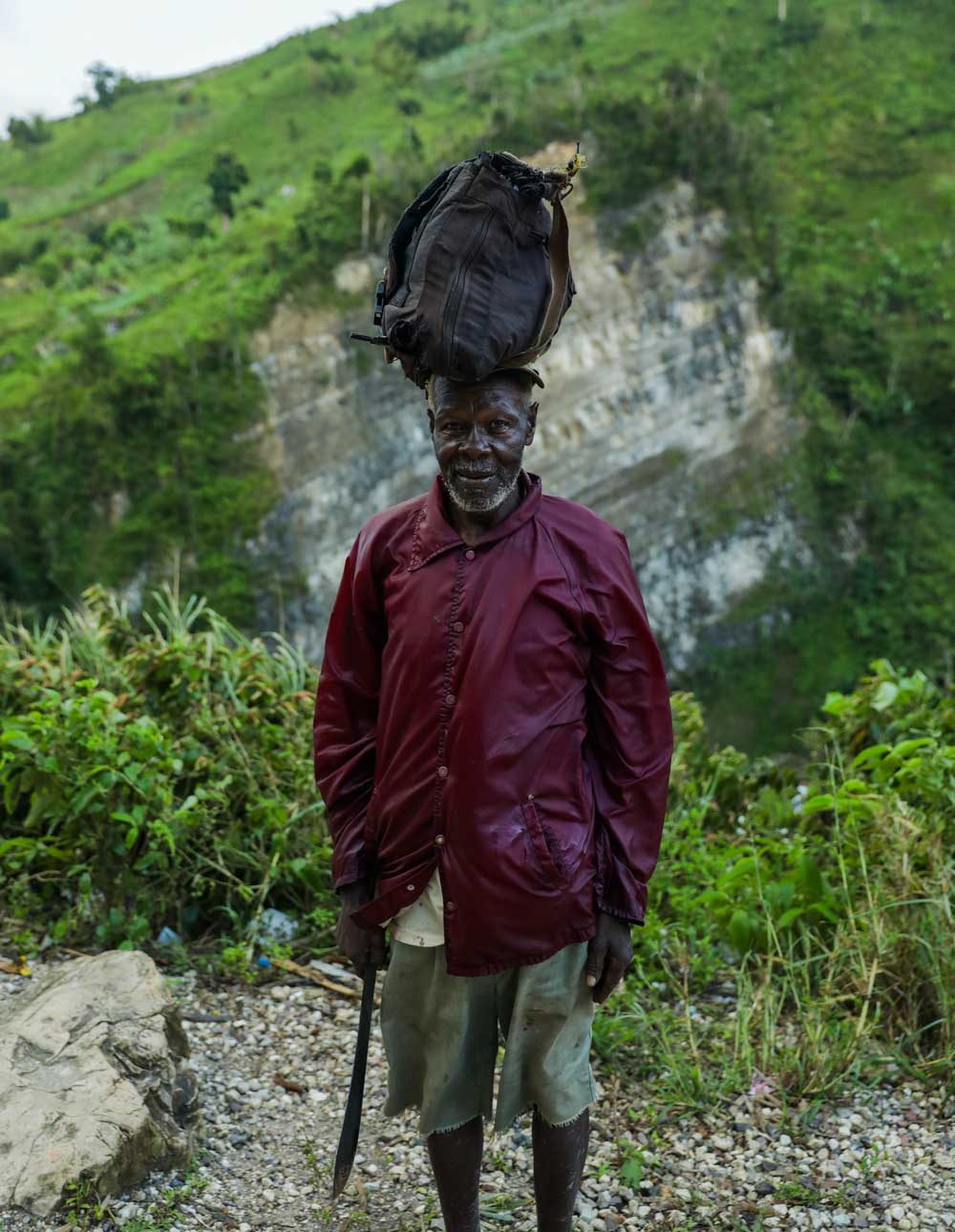 older haitian man with machete and bag on head