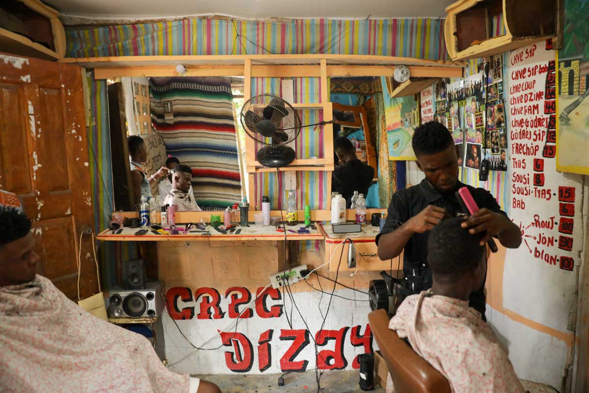 interior of haitian barbershop with clients getting a haircut