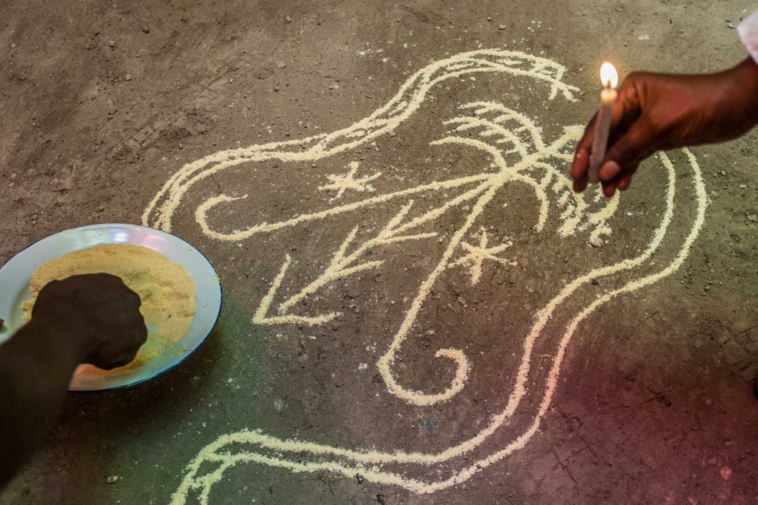 cosmogram being traces on floor with hand holding a candle