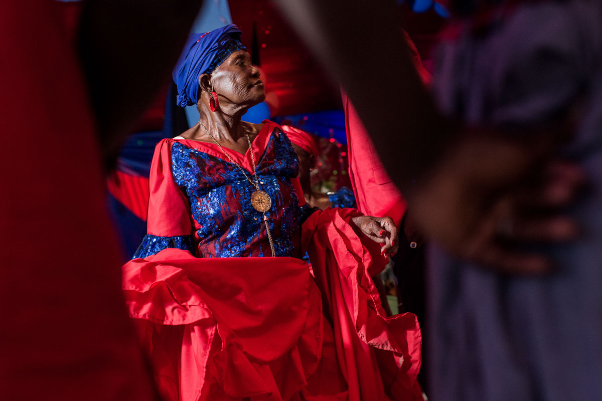older haitian woman in a red dress with blue sequins