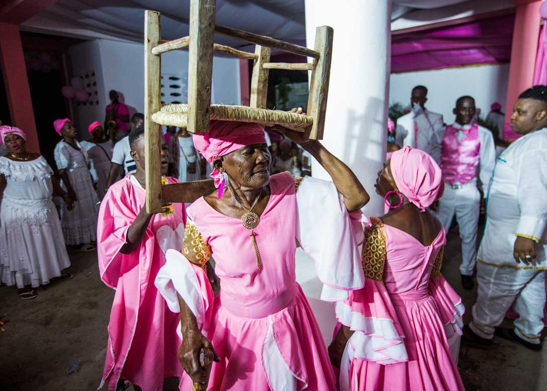 older haitian women dressed in pink with chair on head