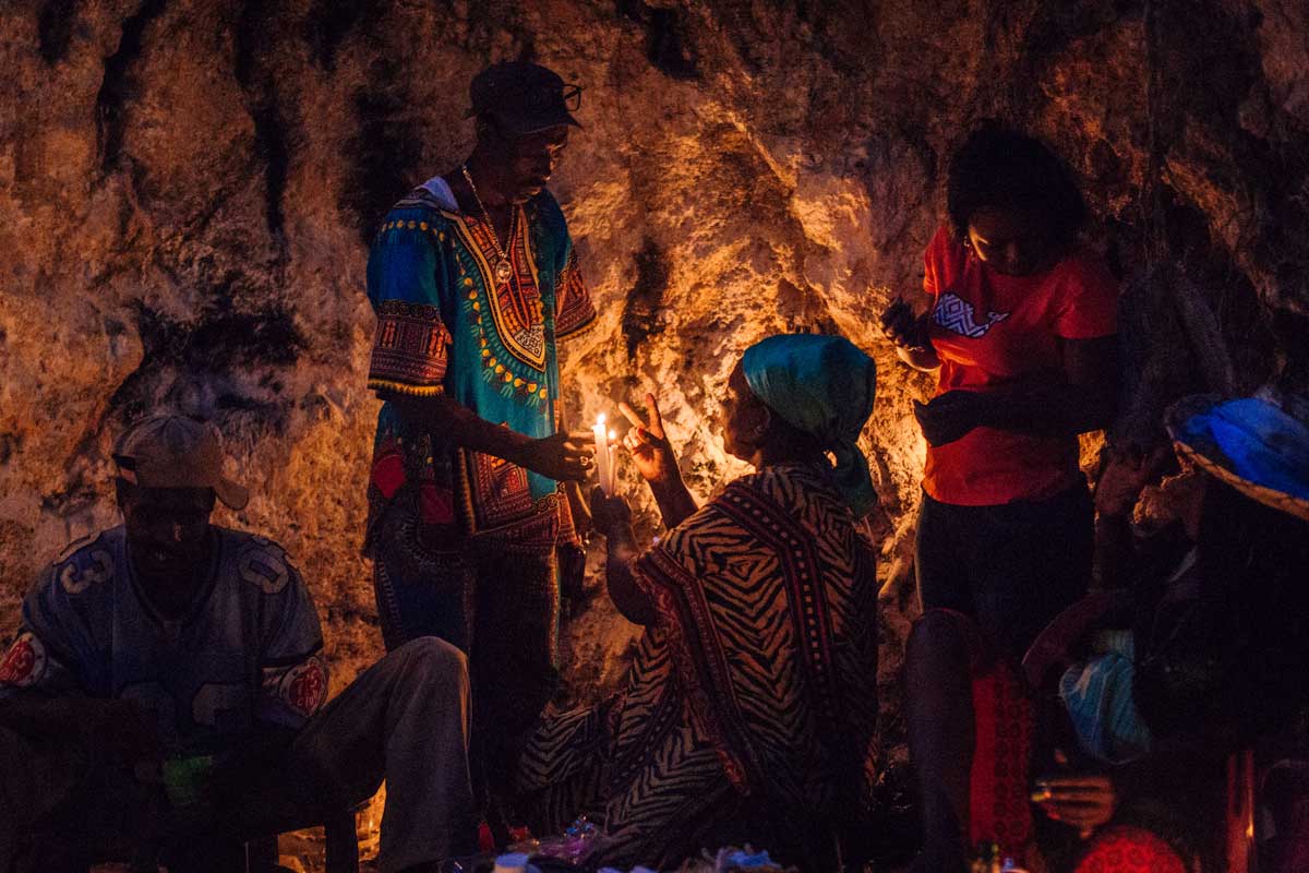 haitian vodou practitioners in dimly lit cave with candles
