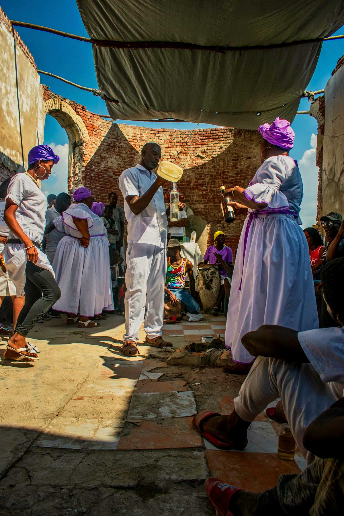 haitian vodou practitioners wearing white filling a transparant bottle with liquid