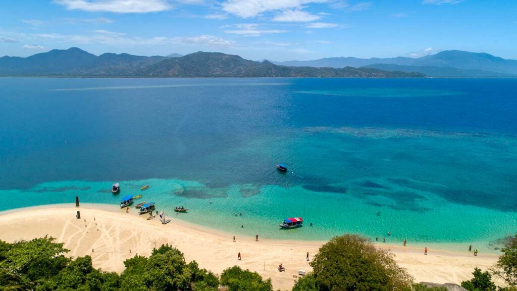 plage de sable blanc sur une île haïtienne avec un océan bleu azur