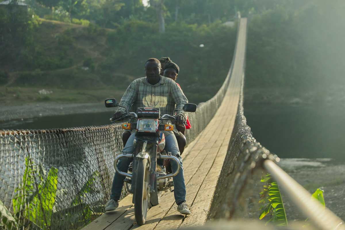 Moto driver crossing suspension bridge in Haiti